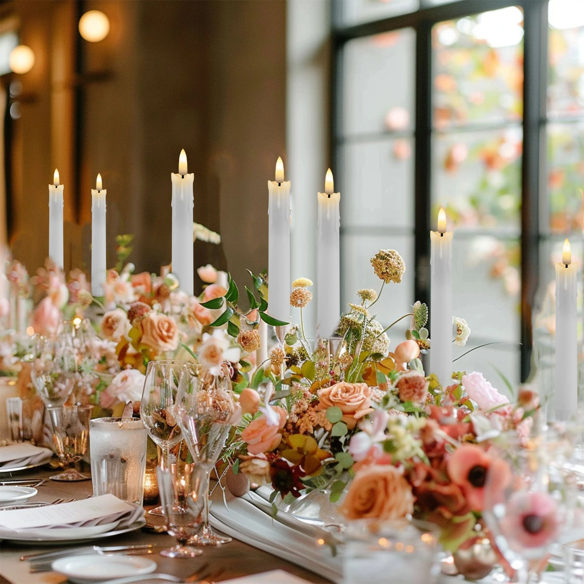 A centerpiece arrangement featuring tall white taper candles and floral accents on a wooden table.