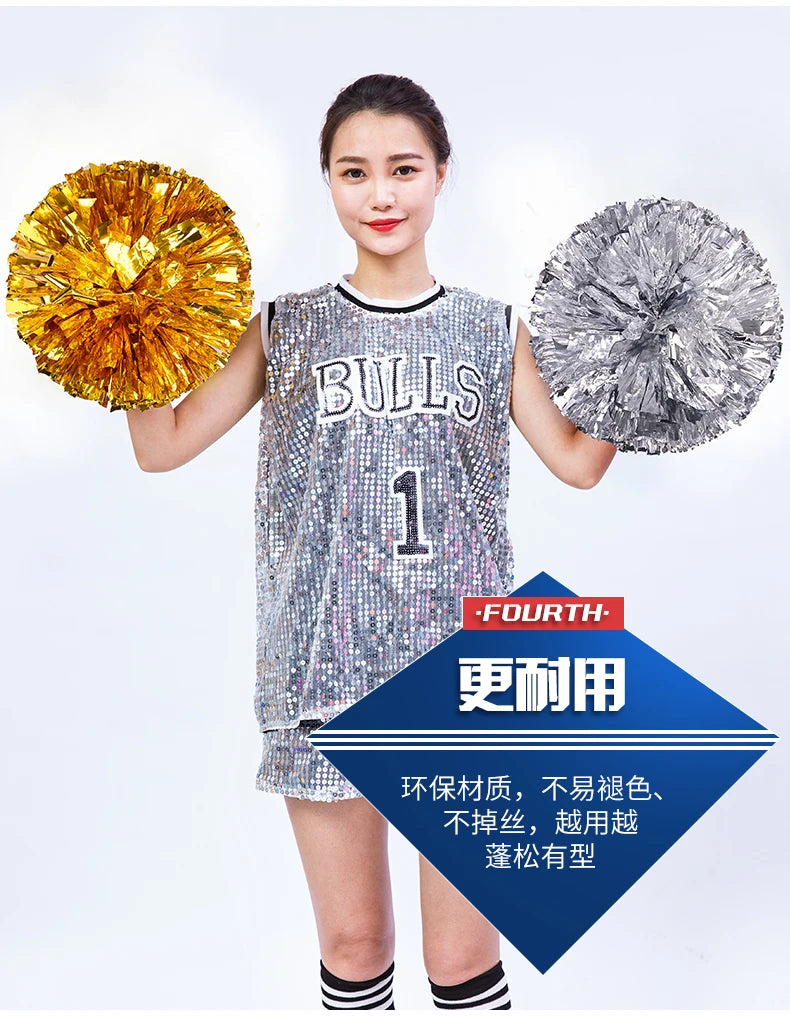 A young woman holds two spherical pom poms, one gold and one silver, against a white background.
