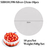 A round white cake board with a silver coating is shown next to a strawberry cake.