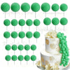 A set of green foam cake toppers, including round and leaf shapes, displayed on white cake bases.