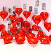 A collection of red heart foil balloons displayed against a white wall.