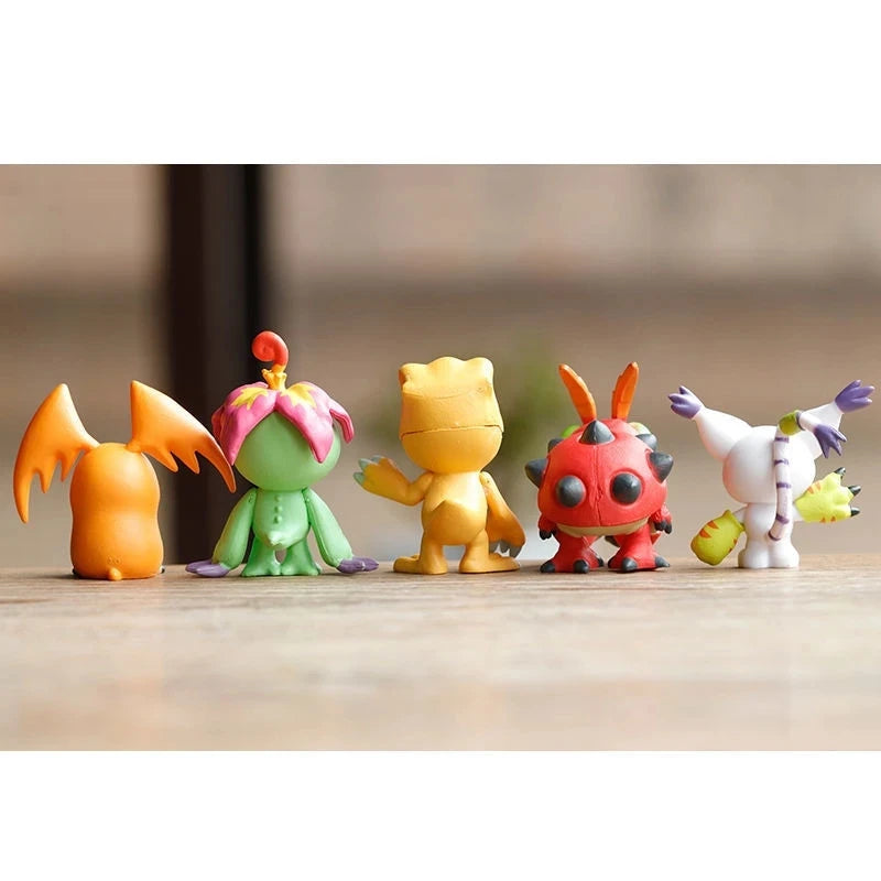 A set of nine colorful Digimon Adventure figures standing in a row on a wooden surface.