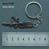 A silver miniature replica of an alloy gun model attached to a keyring, measured against a ruler.