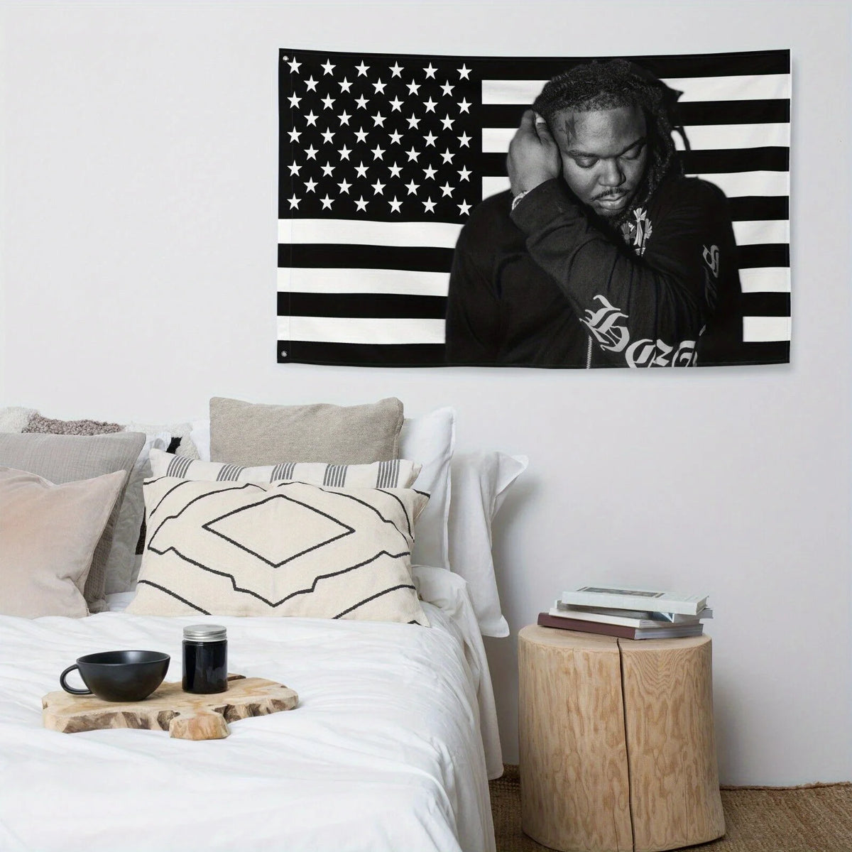 A black and white American flag tapestry banner hanging on a white wall above a bed.