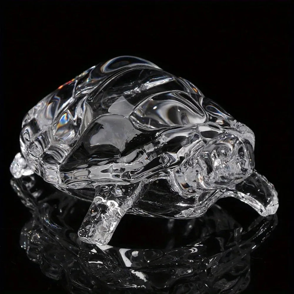 A clear crystal turtle desk ornament reflecting on a dark surface.