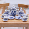 A 15-piece miniature porcelain tea set featuring blue floral patterns displayed on a wooden table.