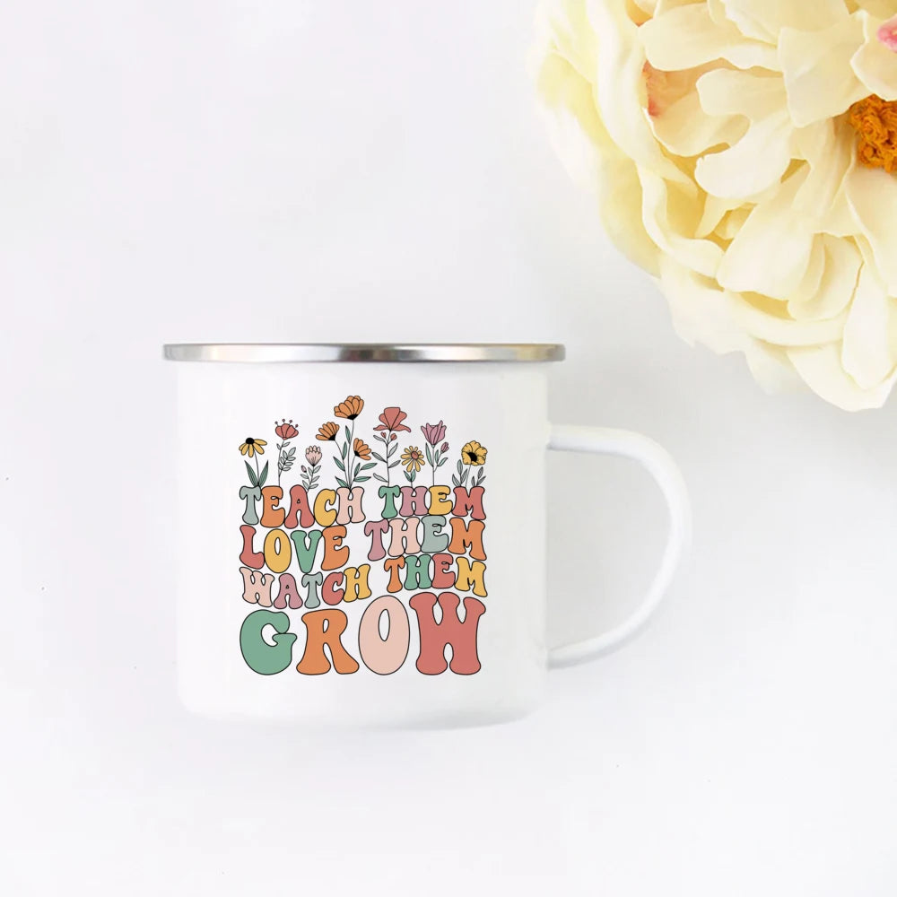 A white enamel mug featuring a floral design with the text Teach them love them watch them grow