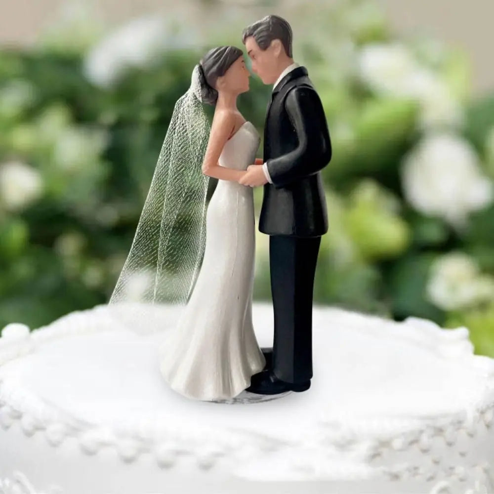 A wedding cake topper featuring an elegant bride and groom figurine in black and white attire.