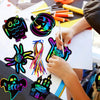 A child is creating Halloween themed scratch art cards using colorful paint and tools on white paper.