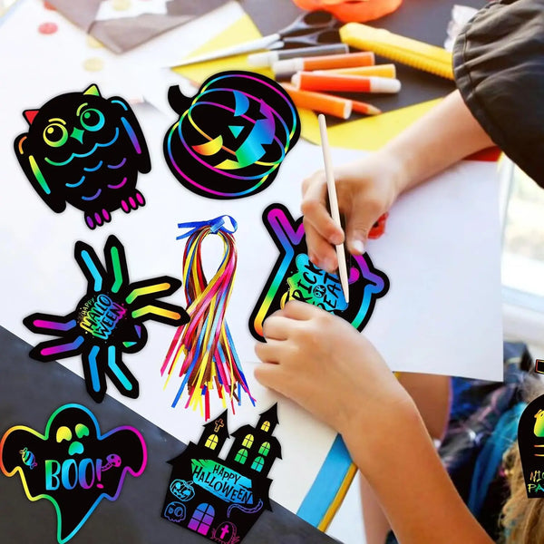 A child is creating Halloween themed scratch art cards using colorful paint and tools on white paper.