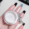 A hand holds a jar of white glitter body highlight powder and a silver crystal bracelet.