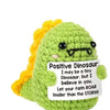 Handmade plush knitting doll shaped like a green dinosaur with yellow hair and a sign that says I may be a tiny dinosaur but 