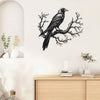 Black raven silhouette on a bare tree branch metal wall art hanging above a wooden cabinet.