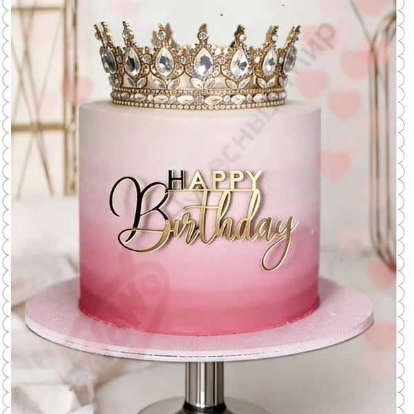 A pink birthday cake with a gold rhinestone crown topper on a stand.