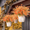 A hanging display of orange and yellow artificial daisies in white pots against a dark background.
