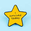 A yellow star enamel pin with black outline featuring the text I survived today.