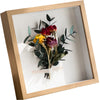 A wooden shadow box photo frame containing a bouquet of deep red and yellow flowers with green foliage.