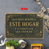 A rectangular metal wall art sign with ornate gold lettering that reads Que Dios bendiga este hogar y a todos los que entran