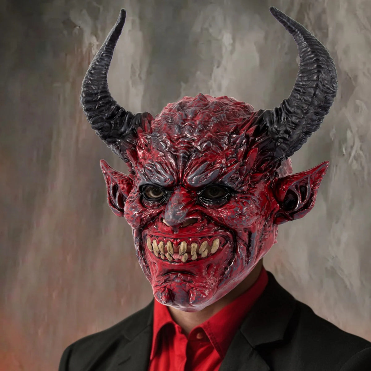 A realistic devil head mask with horns and a fierce expression, painted in deep red and black tones.