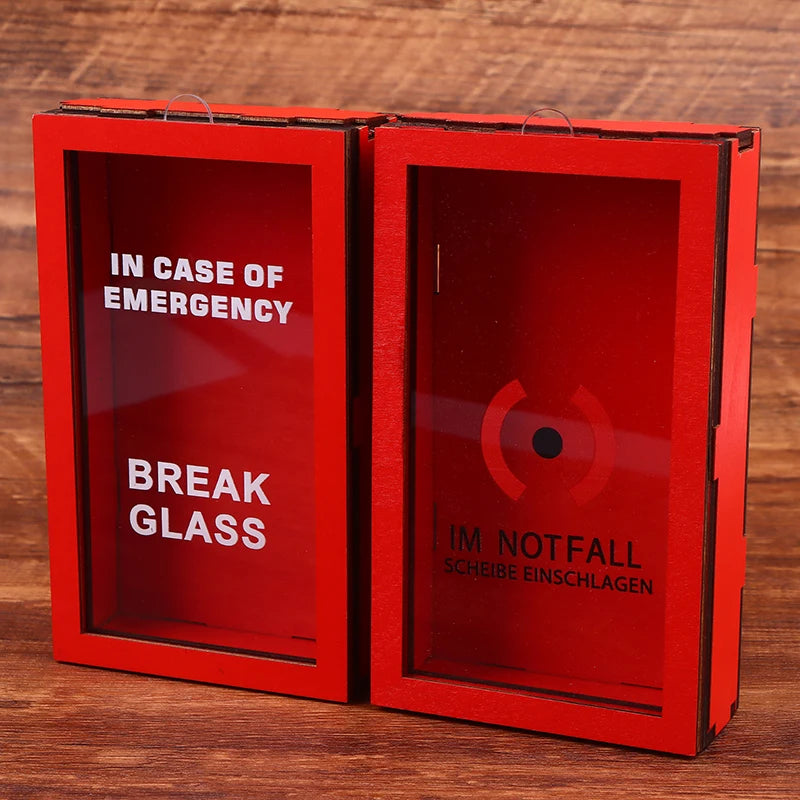 Una caja de regalo roja con dos compartimentos etiquetados 'En Caso de Emergencia' y 'Romper Vidrio