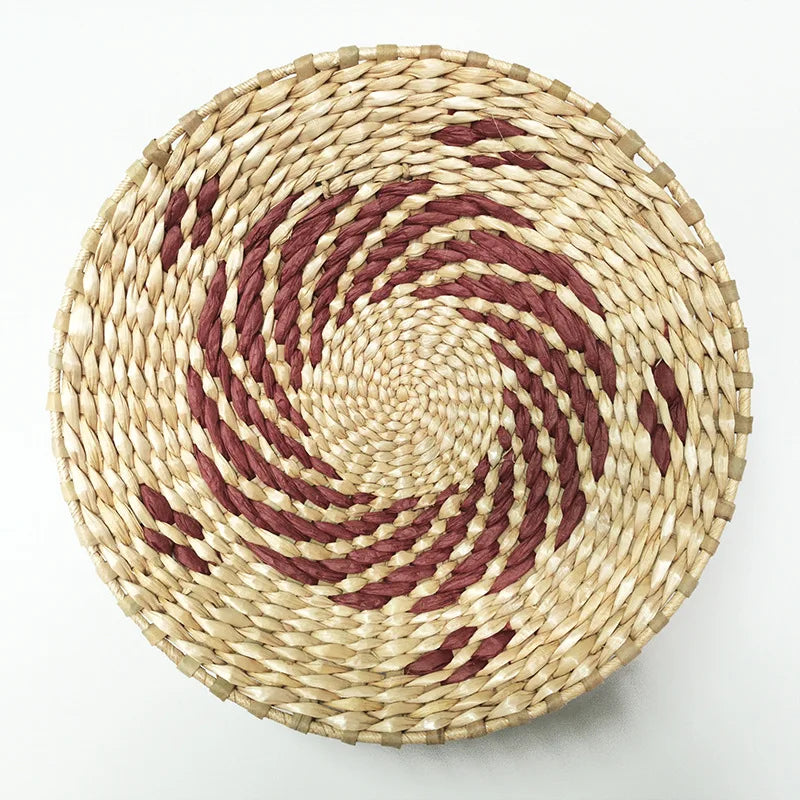 Round woven straw wall decor hanging with concentric spiral pattern in natural beige and reddish-brown tones