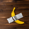 A yellow banana sculpture is crossed by a silver ribbon on a dark wooden surface.