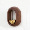A wooden doorbell with a copper bell hanging inside a circular wooden frame.
