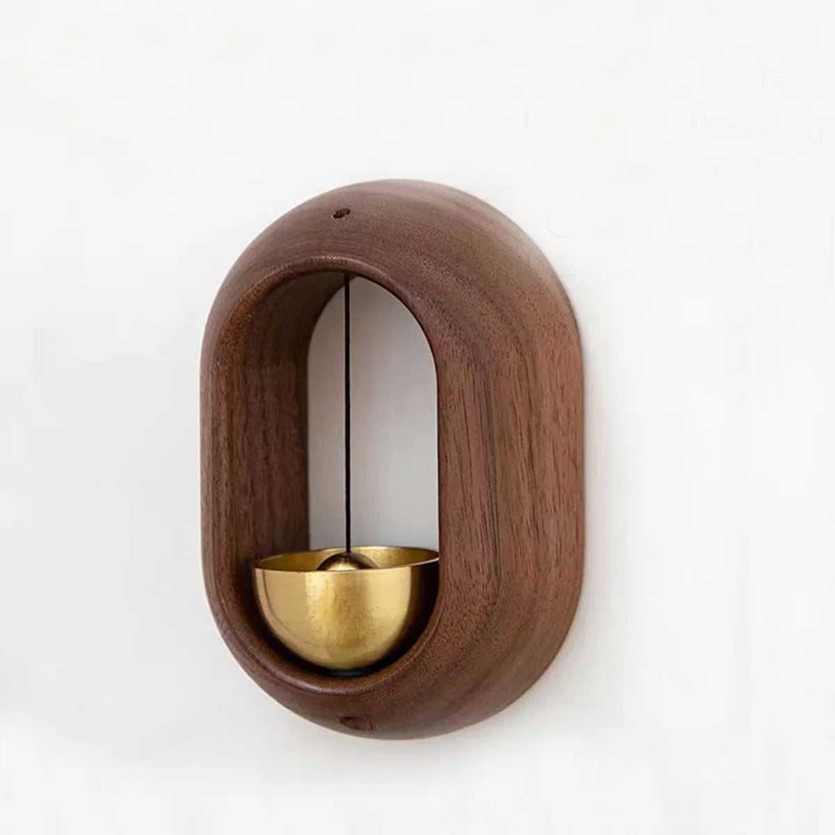 A wooden doorbell with a copper bell hanging inside a circular wooden frame.