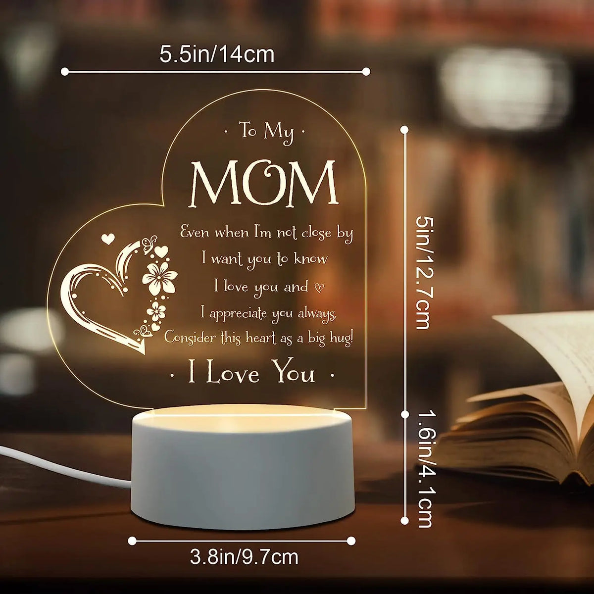 A warm glow night light featuring a heart-shaped sign with a message to Mom and a book in the background.