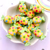 A pile of colorful candy resin cabochons in yellow and pink polka dots arranged on a white dish.