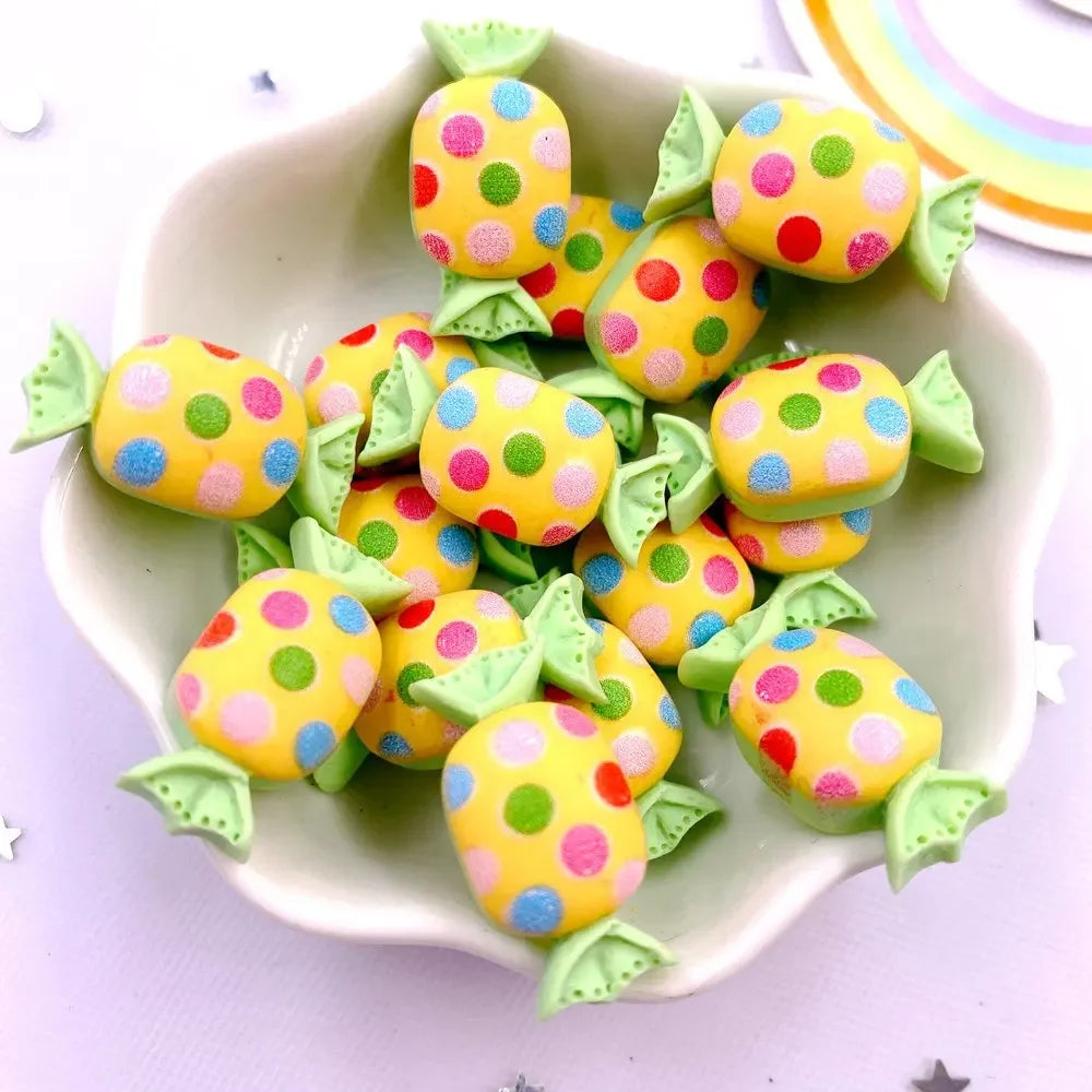 A pile of colorful candy resin cabochons in yellow and pink polka dots arranged on a white dish.