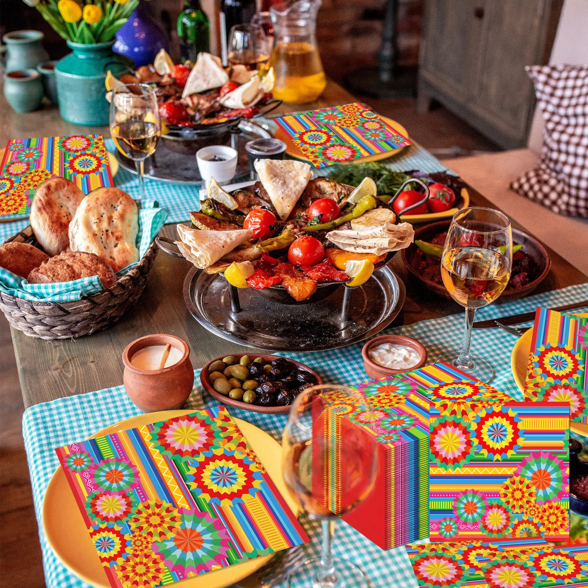 A vibrant Mexican fiesta disposable tableware set laid out on a wooden table with colorful patterned placemats and food.