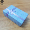 Una caja de regalo azul claro atada con una cinta lavanda sobre una superficie de madera.