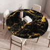 A round black marble print tablecloth with gold veining is displayed on a wooden table in a modern room.