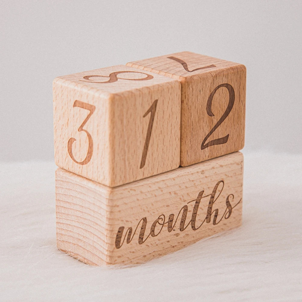 A stack of wooden baby milestone cards showing the numbers 3, 1, 2, and 2 on individual blocks.