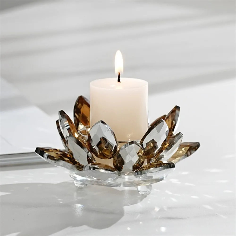 A crystal lotus candle holder with a white tealight candle and gold-toned leaves on a glass dish.