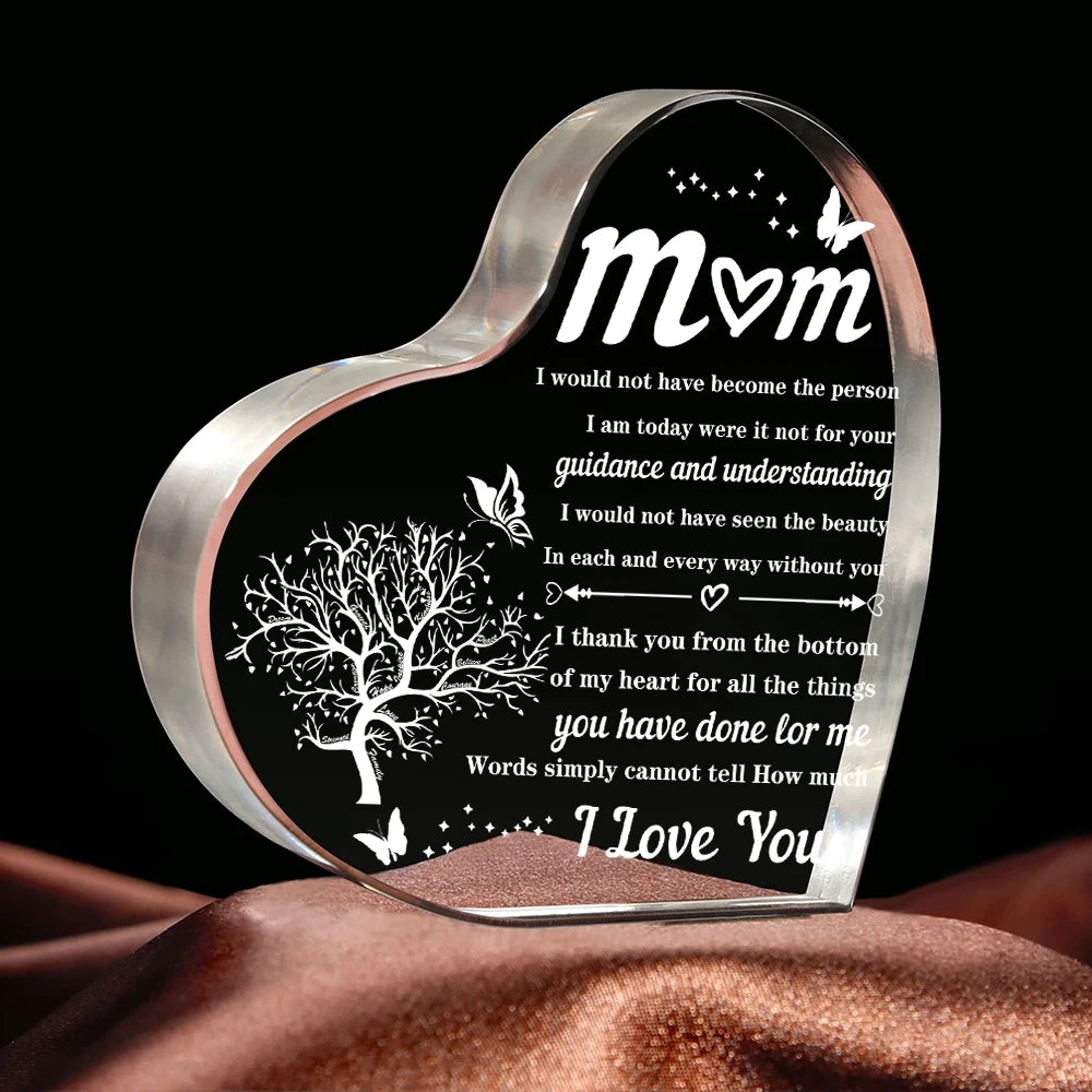 Ornement acrylique en forme de cœur clair gravé d'un message d'amour et de gratitude sur fond sombre.