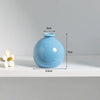 A light blue ceramic mini vase with a rounded body and a narrow neck, shown on a white surface.