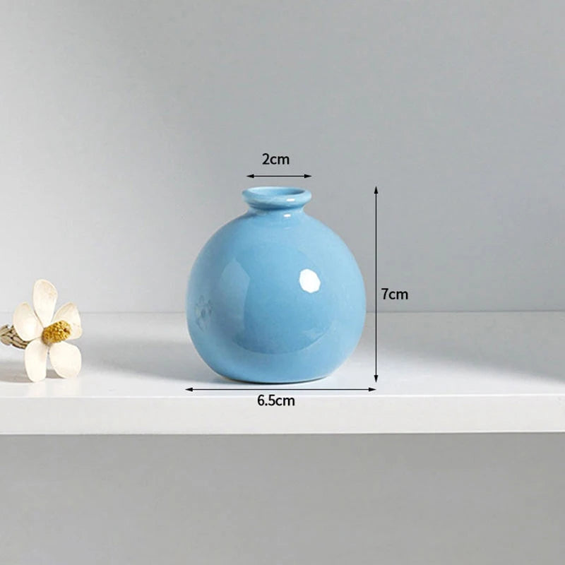 A light blue ceramic mini vase with a rounded body and a narrow neck, shown on a white surface.