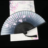 A vintage silk folding fan with gray and black stripes decorated with pink floral patterns, displayed on white paper.