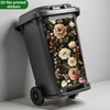 Une poubelle gris foncé avec un autocollant à motif floral sur le côté.