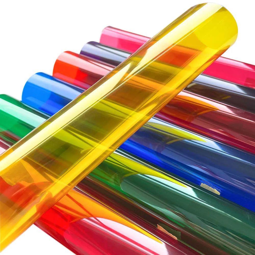 A close-up of decorative stained glass window film rolled up in various vibrant colors like yellow, red, blue, and green.