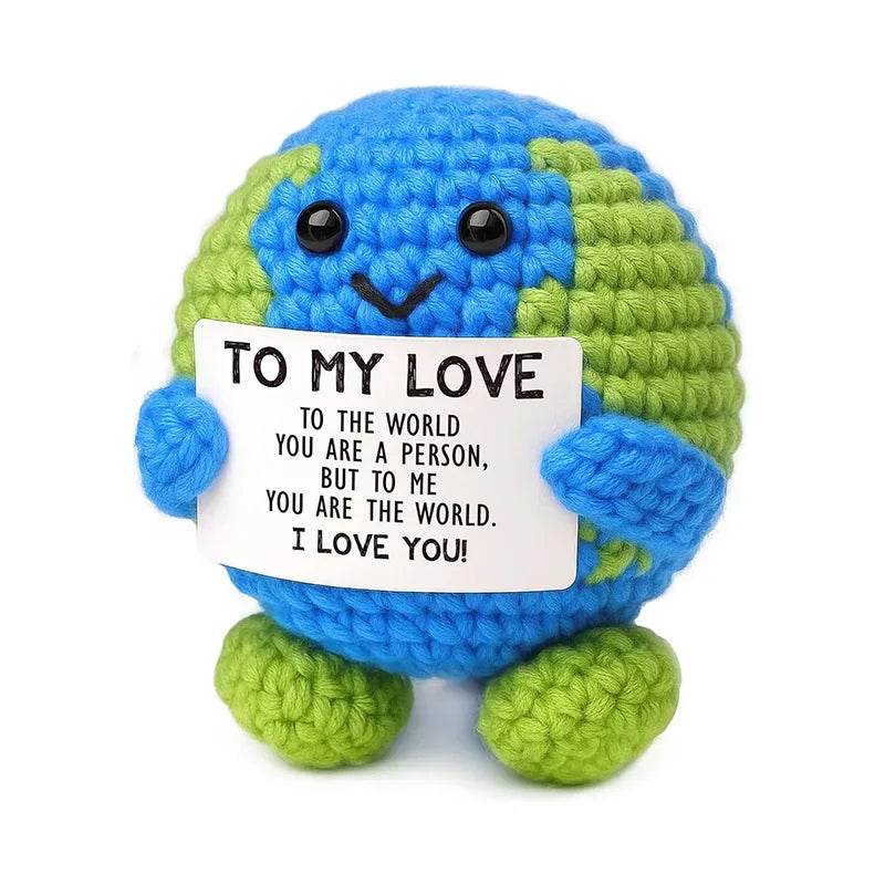 A blue and green crocheted animal doll with a sign that reads To My Love You are a person but to me you are the world I love 