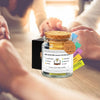 A glass jar filled with yellow liquid and various colored paper cards for a color-coded bible verse jar