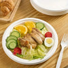 A white plate filled with sliced chicken, cucumber, tomato, and lettuce on a wooden table.