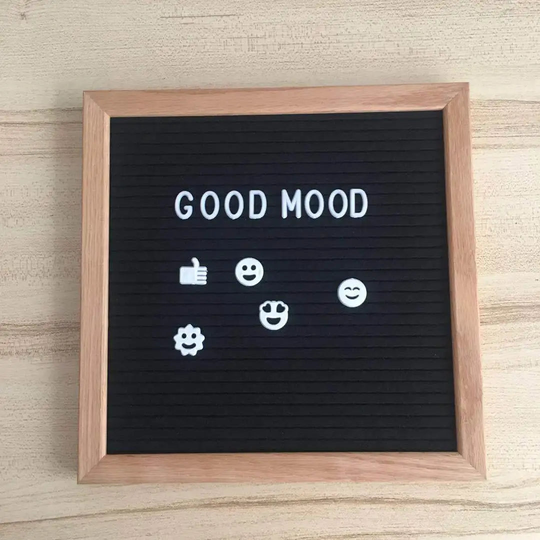 A black felt letter board framed in wood displaying the text GOOD MOOD and various white emoji icons.