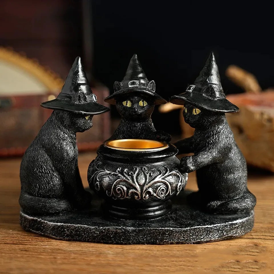 A black figurine of a cat wearing a witch hat sitting on a candle holder.