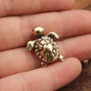 A handcrafted brass turtle figurine resting on a person's hand.