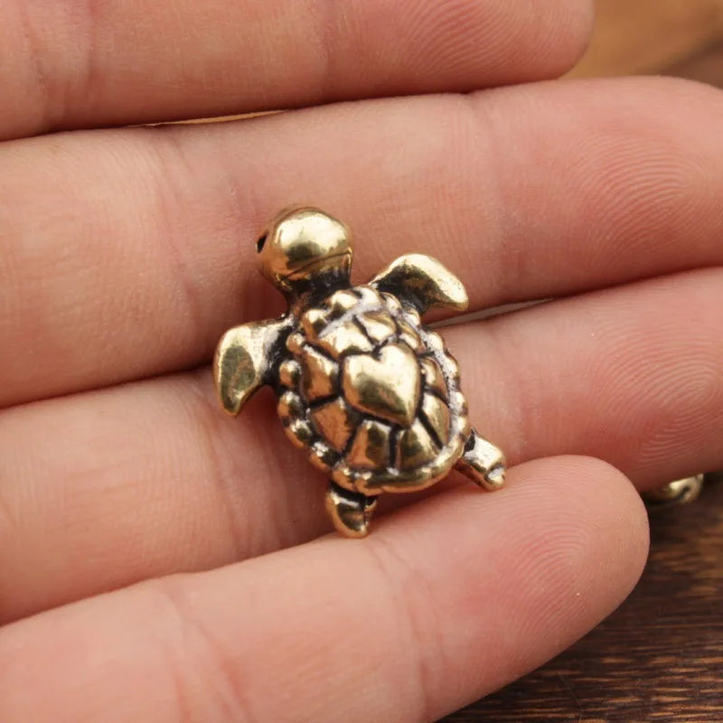 A handcrafted brass turtle figurine resting on a person's hand.
