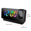 A black projection alarm clock with a large LED display showing 12:00 on a surface.